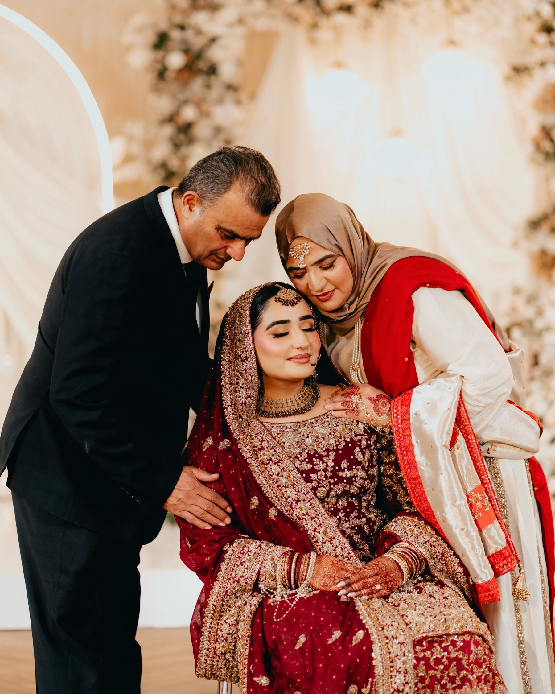 A bride in red is embraced by her family on the wedding day